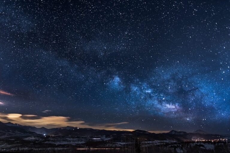 The Milky Way visible over trees and mountains with little light pollution